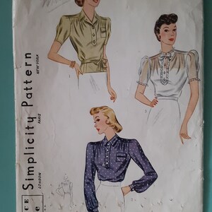 May include: A vintage Simplicity Pattern 3328 envelope for size 16, bust 34. The cover features illustrations of three blouse styles: a short-sleeved olive green shirt, a white blouse with ruffles, and a long-sleeved navy blue shirt with white polka dots.