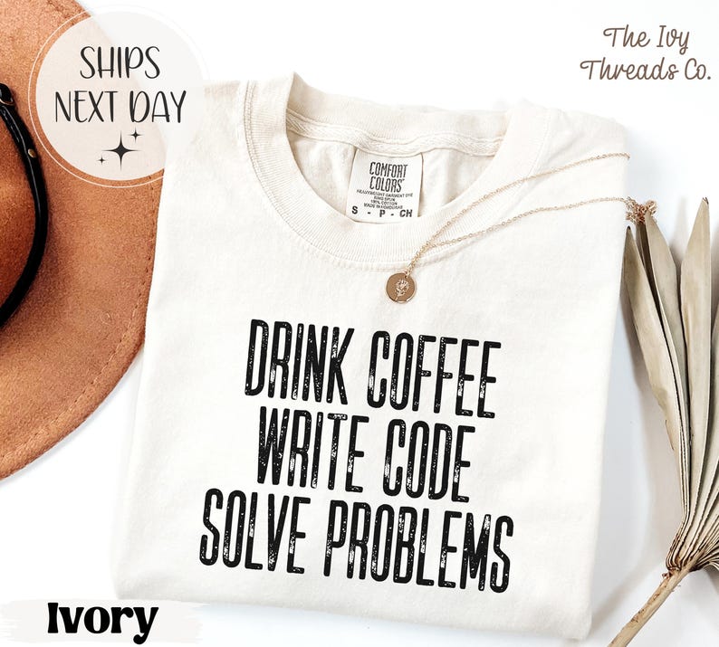 Peut inclure: T-shirt ivoire avec l'inscription noire "DRINK COFFEE WRITE CODE SOLVE PROBLEMS". Le t-shirt a un col rond et des manches courtes. Un collier dor&eacute; avec un pendentif est drap&eacute; sur le t-shirt. Les mots "SHIPS NEXT DAY" sont dans un cercle.