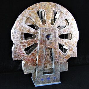 May include: A silver and brown metal model of a Ferris wheel with a blue star design on the base.