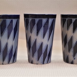 May include: Five ceramic mugs with a blue and white diamond pattern. The mugs are all the same size and shape.