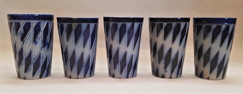 May include: Five ceramic mugs with a blue and white diamond pattern. The mugs are all the same size and shape.