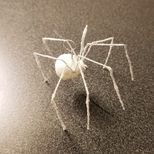 May include: A white, fuzzy spider ornament with a round body and long, spindly legs. The spider has a wire loop at the top for hanging. The legs are made of wire and covered in a fuzzy material. The spider is a Halloween or holiday decoration.