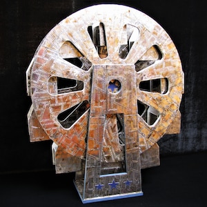 May include: A silver and copper-toned metal sculpture of a Ferris wheel with a blue and white star design on the base.