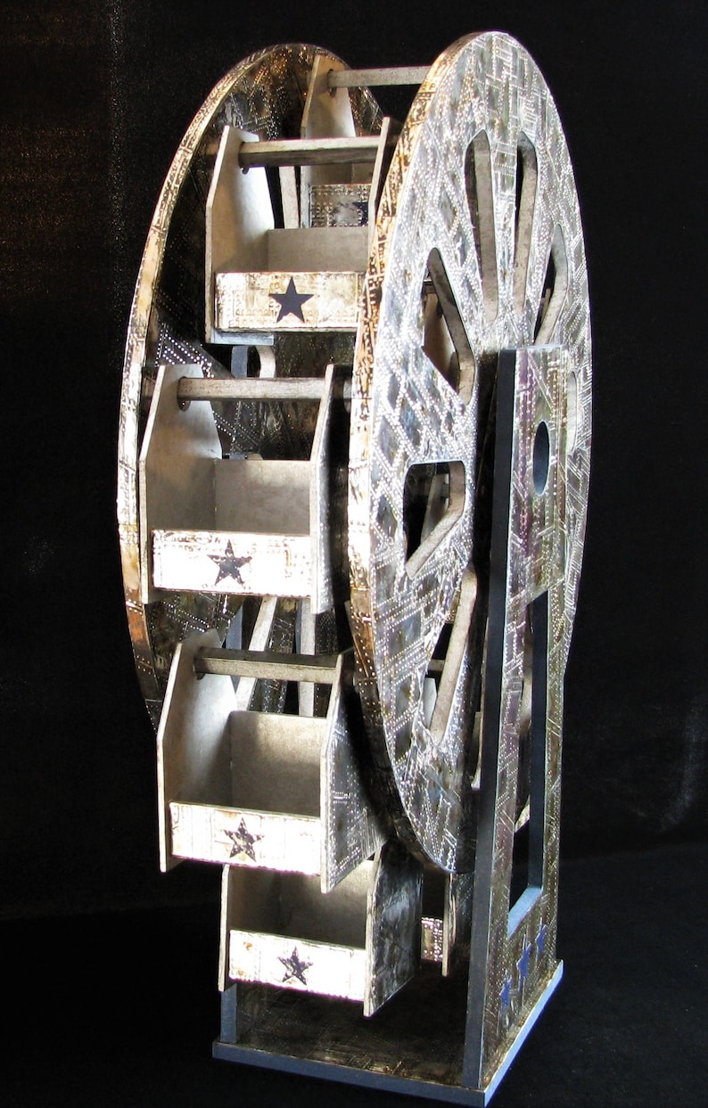 May include: A silver and black wooden Ferris wheel with five shelves. Each shelf has a white background with a black star.
