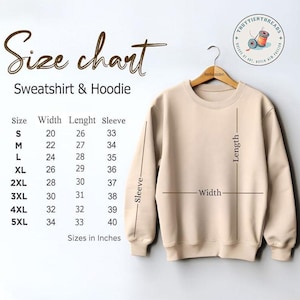 K&ouml;nnte beinhalten: Ein beigefarbenes Sweatshirt h&auml;ngt an einem Holzb&uuml;gel, mit einer Gr&ouml;&szlig;entabelle f&uuml;r Sweatshirts und Hoodies. Die Tabelle listet die Gr&ouml;&szlig;en S bis 5XL auf, mit Ma&szlig;en in Zoll f&uuml;r Breite, L&auml;nge und &Auml;rmel. Der Text "Size chart Sweatshirt & Hoodie" steht oben.