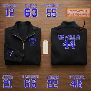 Könnte beinhalten: Schwarzer Pullover mit Viertelreißverschluss und blauen und weißen Buchstaben und Zahlen. Auf der Vorderseite befindet sich ein Briar University-Logo und eine Hockey-Schläger-Grafik. Auf der Rückseite stehen "GRAHAM" und die Nummer "44". Zusätzlicher Text lautet "PASSEN SIE IHREN NAMEN UND IHRE NUMMER AN".