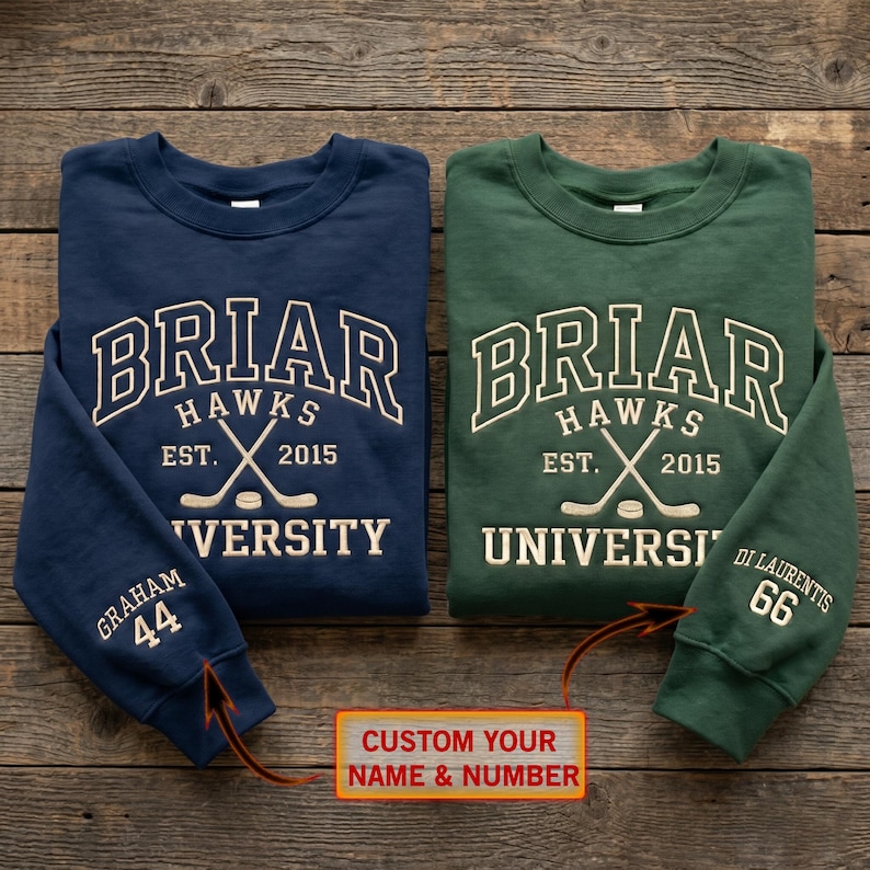 K&ouml;nnte beinhalten: Zwei Rundhals-Sweatshirts, eines in Marineblau und eines in Gr&uuml;n, mit wei&szlig;em gesticktem Text. Das marineblaue Sweatshirt tr&auml;gt die Aufschrift "Briar Hawks University" mit gekreuzten Hockeyschl&auml;gern und dem Namen "Graham" und der Nummer "44" auf dem &Auml;rmel. Das gr&uuml;ne Sweatshirt tr&auml;gt die Aufschrift "Briar Hawks University" mit dem Namen "Di Laurentis" und der Nummer "66" auf dem &Auml;rmel.