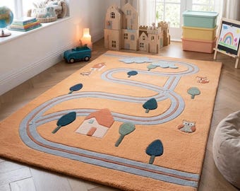 May include: An orange rectangular children's rug with a road design. The rug features a winding road in blue and gray, with houses, trees, and animal figures. The rug is made of a soft material and is designed for a playroom or bedroom.