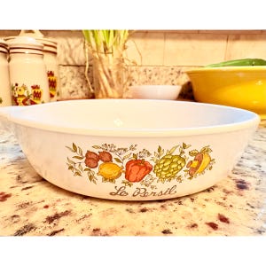 May include: White oval serving dish with a colorful vegetable design. The design includes illustrations of lemons, tomatoes, artichokes, and other vegetables. The words "Le Persil" are written in script below the vegetables.