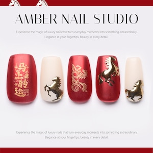 May include: Five artificial nails with a red and cream colour scheme. The nails feature gold horse and dragon designs. The text "AMBER NAIL STUDIO" is at the top. The nails are for nail art.