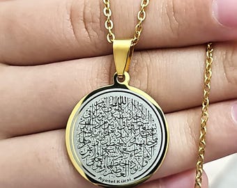 Può includere: Collana con catena dorata e un ciondolo rotondo con calligrafia araba nera su sfondo argentato. Il ciondolo ha la scritta "Ayet el Kursi" incisa nella parte inferiore.