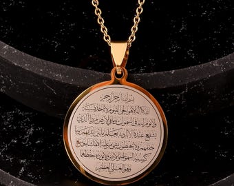 May include: A gold-tone necklace with a round pendant featuring an inscription in Arabic script. The pendant is engraved with the text "بسم الله الرحمن الرحيم الله لا اله الا هو الحي القيوم لا تاخذه سنة ولا نوم له ما في السموات وما في الارض مردا الذي يشفع عنده الا باذنه يعلم ما بين ايديهم وما خلفهم ولا يحيطون بشيء من علمه الا بما شاء وسع كرسيه السموات والارض ولا يئوده حفظهما وهو العلي العظيم".