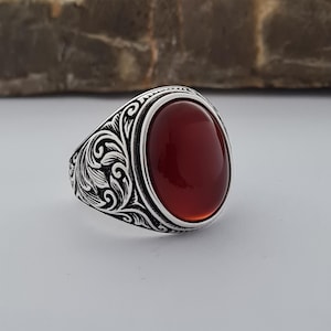 Può includere: Un anello d'argento con un design floreale ornato e una pietra di corniola rossa.