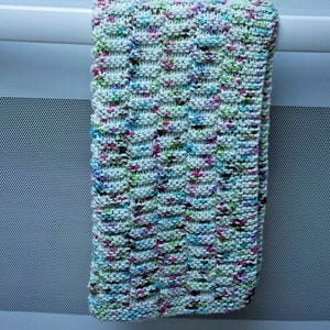 May include: A white knitted dishcloth with a textured pattern and multicolored flecks of pink, green, blue, and brown.