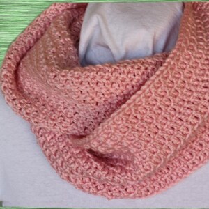 May include: A pink crocheted infinity scarf. The scarf is made with a simple stitch and is a great accessory for any outfit.