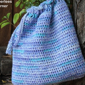 Puede incluir: Un bolso de ganchillo hecho a mano con cord&oacute;n en tonos azules y morados. El bolso presenta un patr&oacute;n de puntadas texturizadas y una parte superior fruncida con cierre de cord&oacute;n. El bolso est&aacute; hecho de hilo suave y es adecuado para llevar varios art&iacute;culos.