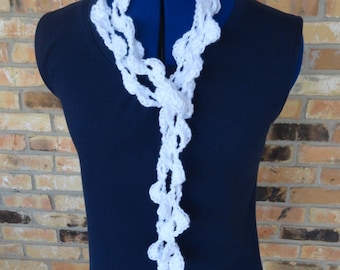 May include: White crocheted scarf with a delicate, lacy design. The scarf is draped over a blue mannequin and is long enough to be worn as a necklace or a shawl.