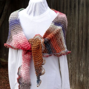 May include: A colorful crocheted shawl with a scalloped edge. The shawl is tied around the neck and draped over the shoulders.