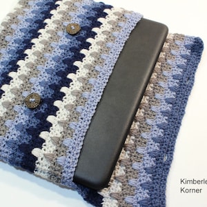May include: Crocheted laptop sleeve in shades of blue, gray, and white, featuring a textured stitch pattern. The sleeve has two decorative buttons and a dark gray laptop inside. The text "Kimberlees Korner" is visible.