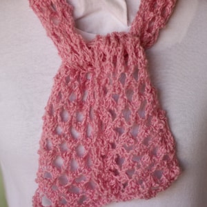May include: A pink crocheted scarf with a delicate openwork pattern. The scarf is made of soft yarn and has a lightweight feel.