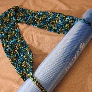 Puede incluir: Una esterilla de yoga azul con la palabra "GAIAM" impresa en ella está envuelta en una correa de crochet de colores.