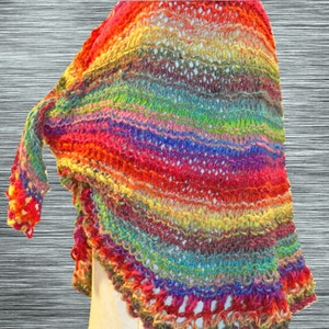 May include: A colorful crocheted shawl with a rainbow pattern. The shawl is made with a variety of yarn colors, including red, orange, yellow, green, blue, indigo, and violet.