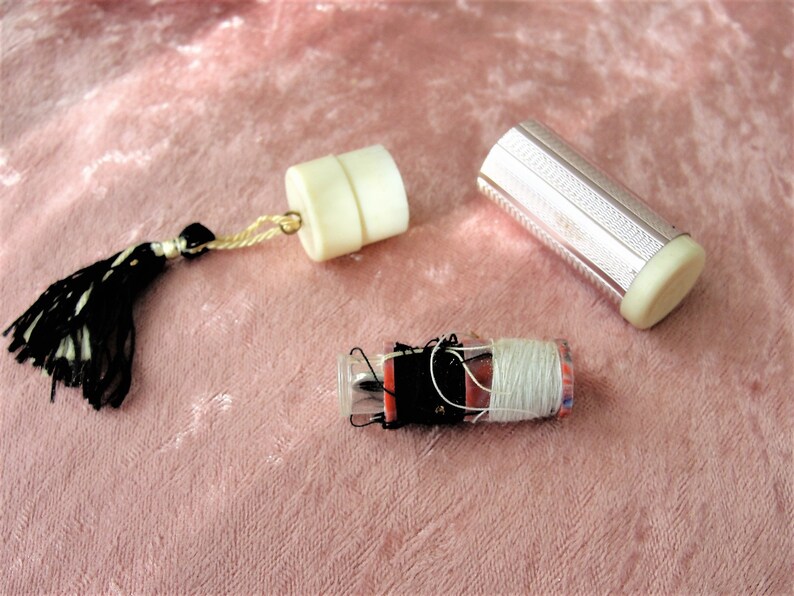 May include: Three vintage sewing kits with white and silver metal cases. One kit has a black and white tassel. The kits contain thread, needles, and other sewing supplies.