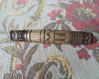 May include: A wooden spindle with intricate carvings. The spindle is brown and has a series of geometric patterns carved into its surface.
