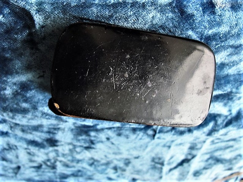 May include: A black rectangular box with a smooth, slightly textured surface. The box has a slightly rounded edge and appears to be made of a hard material.