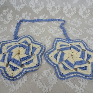 May include: A pair of crocheted pot holders in the shape of stars. The pot holders are made with blue and white yarn and have a hanging loop.