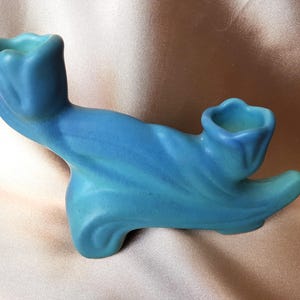 Op de afbeelding: Een blauwe keramische kandelaar met twee bloemvormige bekers. De kandelaar heeft een vloeiend, organisch ontwerp met een verloop van blauwtinten. Het stuk is waarschijnlijk vintage of antiek.