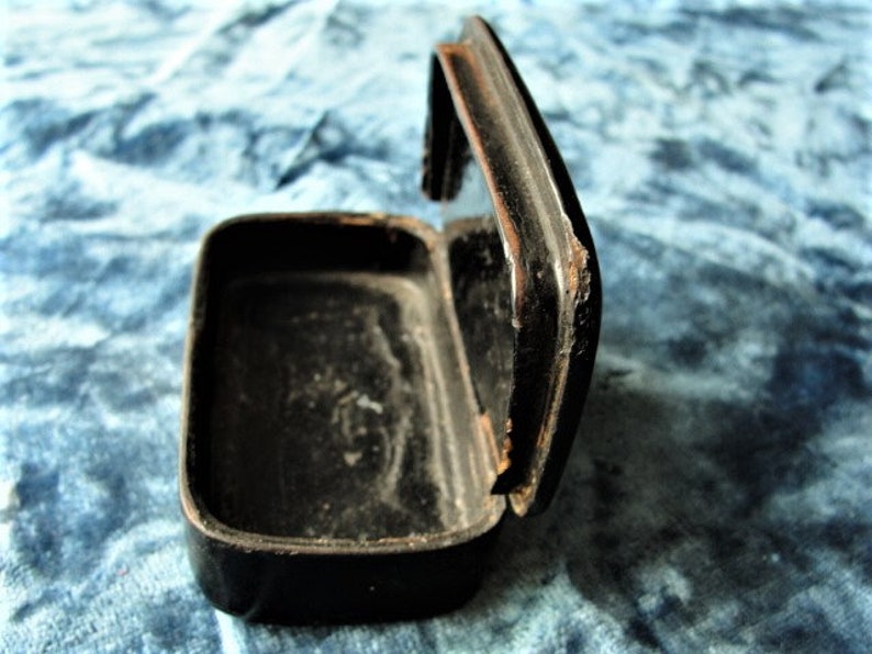 May include: A black wooden box with a hinged lid. The box is open and the inside is empty.