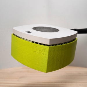 Op de afbeelding: Een kleine, vierkante aquariumwaterpomp in wit en groen met een zwarte slang eraan bevestigd. De pomp heeft een zwart rond filter en de tekst "Seadream" staat er op gedrukt.