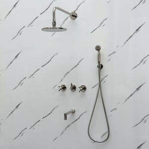 May include: A modern shower fixture set with a polished nickel finish. The set includes a round rain shower head, a handheld shower, three cross-handle valves, and a spout. The fixtures are mounted on a white marble-patterned wall.