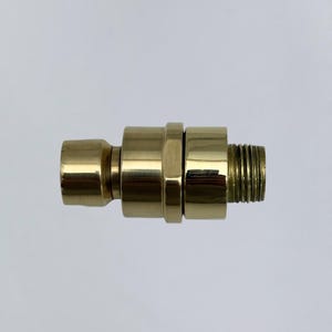 Puede incluir: Un conector de color latón con un extremo roscado macho, un extremo hembra y una sección cilíndrica central. El conector está diseñado para unir dos componentes. La superficie es lisa y reflectante, con un ligero brillo.