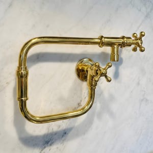 Puede incluir: Una taza de cerámica blanca con un asa negra y el texto "But First, Coffee" en negrita negra. La taza está sobre una superficie de madera. La taza mide 10 cm de alto.