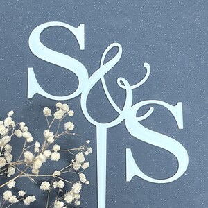 以下が含まれることがあります： スタイリッシュなスクリプトフォントでアンパサンドによって接続されたSとSの文字を特徴とする白いアクリルのケーキトッパー。トッパーには、ケーキに挿入するためにアンパサンドの底部から伸びる単一の垂直なステークが含まれています。