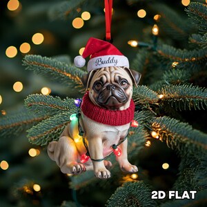 Könnte beinhalten: Ein Weihnachtsbaumschmuck in Form einer Mops-Figur, die einen roten Weihnachtsmannhut mit dem Namen "Buddy" und einen roten Schal trägt. Der Mops ist mit einer Lichterkette geschmückt. Der Anhänger hängt an einem roten Band vor einem Weihnachtsbaum.