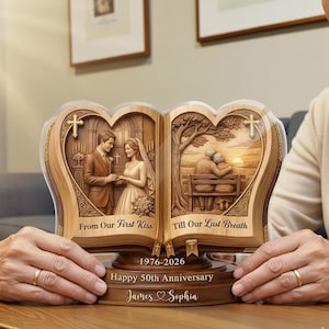 Puede incluir: Un recuerdo de aniversario de madera con un diseño en forma de corazón. El recuerdo presenta imágenes talladas de una pareja en su boda y más tarde en la vida. El texto incluye "From Our First Kiss", "Till Our Last Breath", "1976-2026", "Happy 50th Anniversary" y nombres.