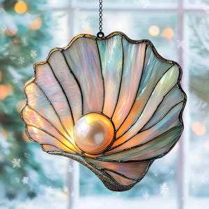 Peut inclure: Un attrape-soleil en vitrail en forme de coquillage ouvert avec des panneaux de verre irisés et multicolores et une sphère centrale ronde de couleur crème ressemblant à une perle. L'objet est encadré de soudure métallique sombre et suspendu à une fine chaîne.
