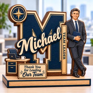 Puede incluir: Un letrero de escritorio de madera en capas con una letra M grande, un icono de brújula y una figura de un profesional en traje sosteniendo una carpeta. El letrero incluye el texto Michael, Team Leader y Thank You for Leading Our Team en azul.