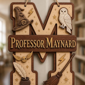 Könnte beinhalten: Holzschild in Form des Buchstabens "M" mit Zaubererthema. Das Schild zeigt einen Zaubererhut, eine Eule, einen Besen und den Text "PROFESSOR MAYNARD". Das Schild besteht aus geschichtetem Holz mit natürlichem Finish und wird von einem Seil gehalten.