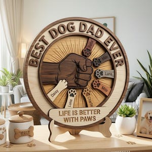 May include: A wooden circular sign with the text "BEST DOG DAD EVER" and a fist graphic. The sign includes paw prints and names, with the phrase "LIFE IS BETTER WITH PAWS" below. It is displayed on a wooden stand.