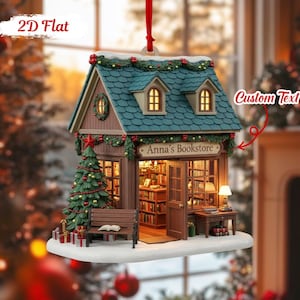 Puede incluir: Adorno de librería en miniatura con tejado turquesa, árbol de Navidad y el texto "Anna's Bookstore". El adorno presenta un banco, regalos y un cálido resplandor interior.