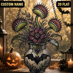 May include: A hanging stained glass-style ornament featuring three green and red Venus flytraps and a central purple flower in a vase decorated with a black bat and purple gems. The text CUSTOM NAME and 2D FLAT appear at the top, with Anna written on the side.