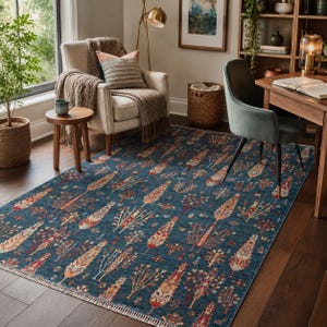 May include: A rectangular area rug featuring a deep blue background with a repeating pattern of stylized trees in shades of rust, cream, and muted gold. The rug has a short fringe along the edges and is positioned on a dark wood floor.