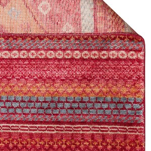 May include: A rectangular area rug featuring a vibrant red base color with horizontal bands of intricate geometric patterns in shades of orange, light blue, and cream. The rug has a textured pile surface and a folded corner revealing the underside.