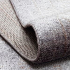 May include: A rolled area rug featuring a light gray and beige color palette with a faded, distressed pattern. The rug has a soft, textured pile surface and a finished, stitched edge that follows the curve of the roll, revealing the backing.