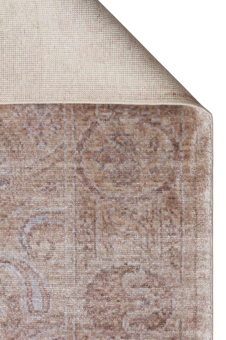 May include: A rectangular area rug featuring a faded, distressed pattern in shades of taupe, beige, and soft blue. The rug has a visible woven backing in a light cream color, with one corner folded over to reveal the textured underside and edge.