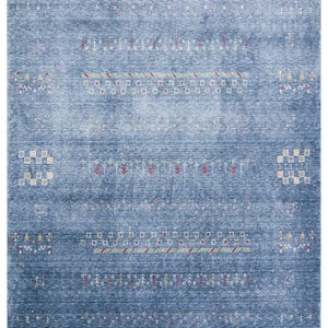 May include: A rectangular area rug in a deep blue hue with a distressed, mottled texture. The rug features horizontal rows of small, intricate geometric patterns in white, red, and yellow, finished with short, light-colored fringe at both ends.